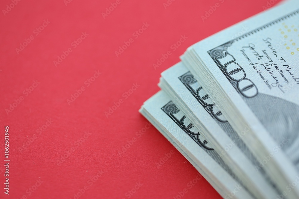 Big amount of hundred dollar bills in thick stack lies on bright red color paper background Big amount of hundred dollar bills in thick stack lies on bright red color paper background