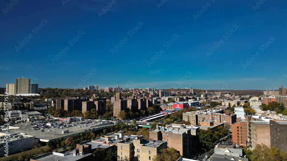 Naklejka premium This location in the Bronx offers stunning views of lush greenery, a picturesque lake, and urban structures. Framed by the river, it showcases iconic bridges and the New York City skyline in the dista