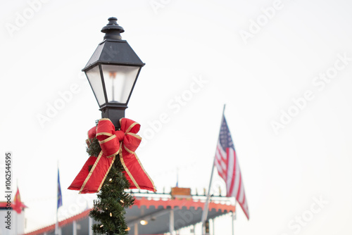 Christmas bow, garland, and lights decor on a lamp post in front of harbor