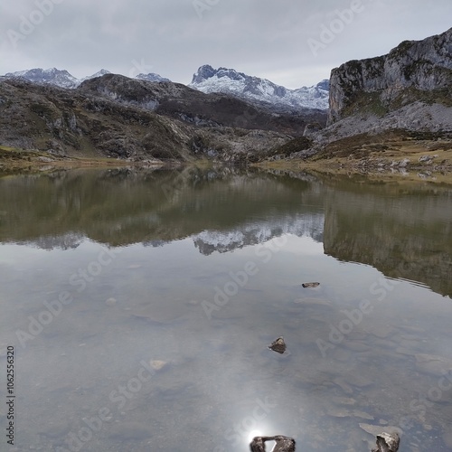 A serene lake reflecting the snowy mountains creating a perfect symmetry, evoking a sense of solitude and peacefulness in a natural and untouched setting.