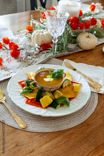 Pumpkin Ravioli with summer squash around a bowl of pumpkin and ginger soup