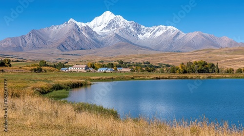 Serene Mountain Lake with Houses and Snow Capped Peaks