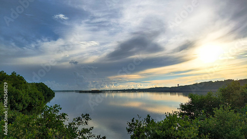 Serene Sunset over River Landscape with Vibrant Clouds and Reflections on Water Surface