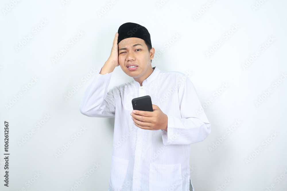 muslim asian man holding phone with touching his head feeling dizzy isolated muslim asian man holding phone with touching his head feeling dizzy isolated