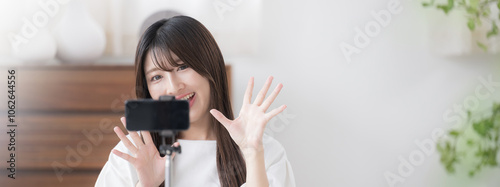 撮影する動画配信者のイメージ　かわいい若い女性がカメラに向けてバイバイと手を振るバナー