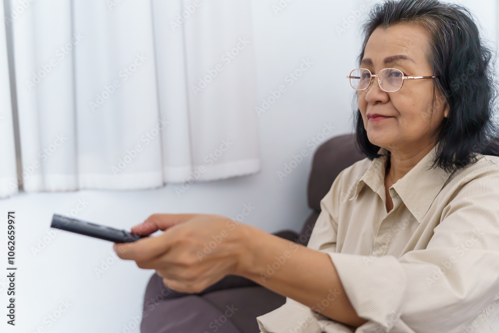 Elderly woman Watching smart TV and using remote controller Hand holding television audio remote control Middle age Asian woman movie Television series spending time at home Elderly woman Watching smart TV and using remote controller Hand holding television audio remote control Middle age Asian woman movie Television series spending time at home