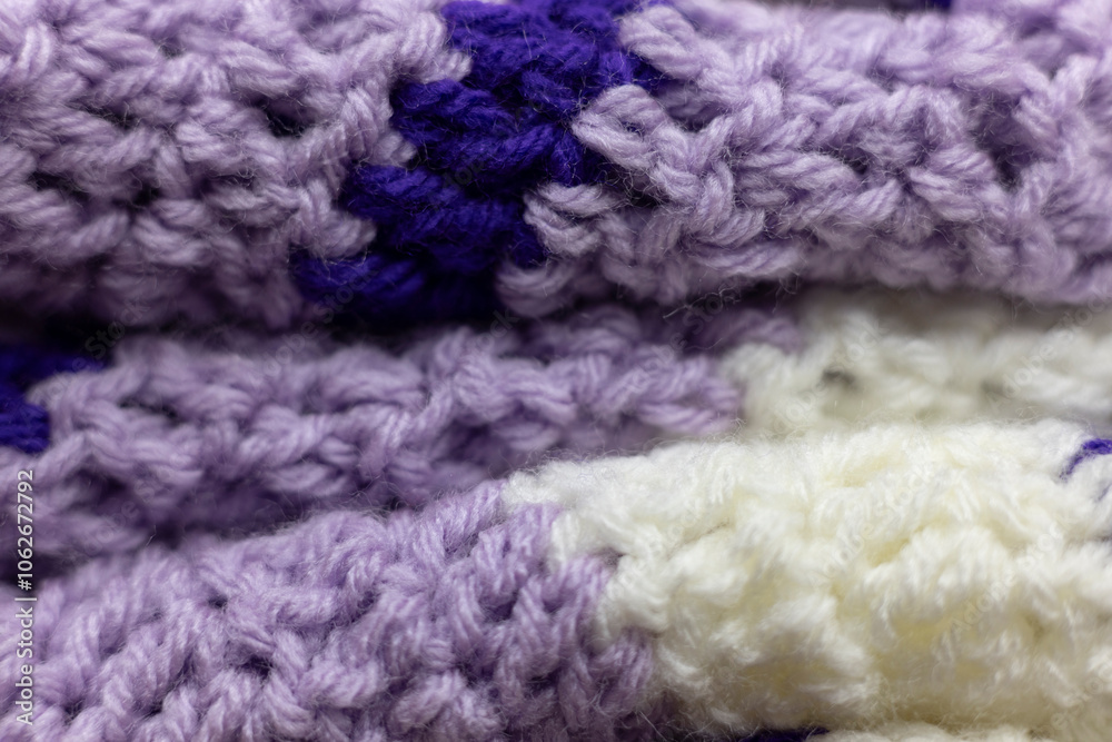 close-up of folded lilac purple zigzag blanket with white and royal purple accents, crocheted or knitted, reminds you of grandma's house, cozy and warm background close-up of folded lilac purple zigzag blanket with white and royal purple accents, crocheted or knitted, reminds you of grandma's house, cozy and warm background