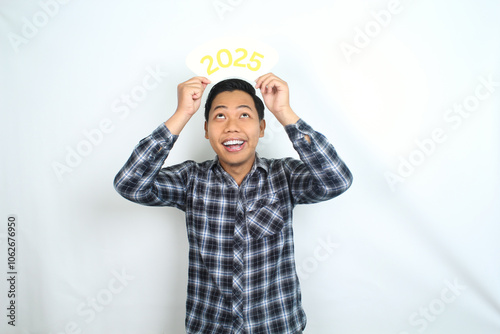 Canvas Print attractive asian man smiling with holding 2025 card and looking above to celebra