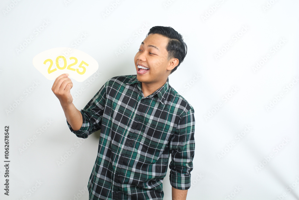 attractive and carefree asian man holding 2025 new years eve greeting card wearing casual plaid clothes isolated on white background attractive and carefree asian man holding 2025 new years eve greeting card wearing casual plaid clothes isolated on white background