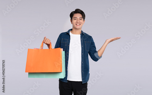 Portrait of young Asian man holding a  shopping bag  and posing on a white background photo