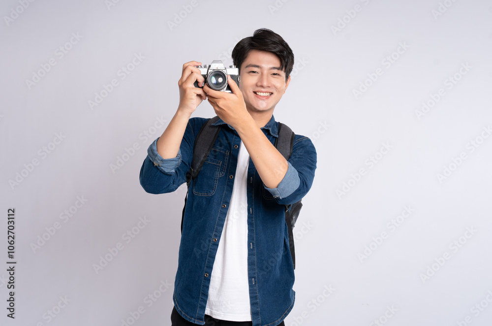 Portrait of young Asian man holding travel camera and posing on white background Portrait of young Asian man holding travel camera and posing on white background