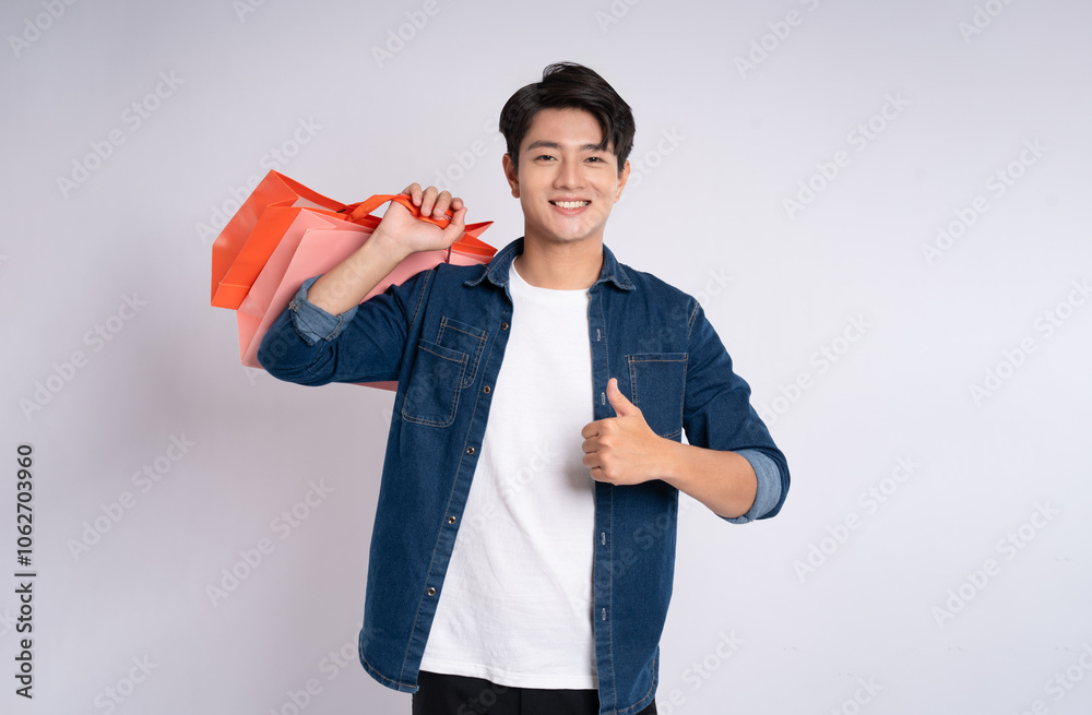 Portrait of young Asian man holding shopping bag posing on white background
Portrait of young Asian man holding shopping bag posing on white background