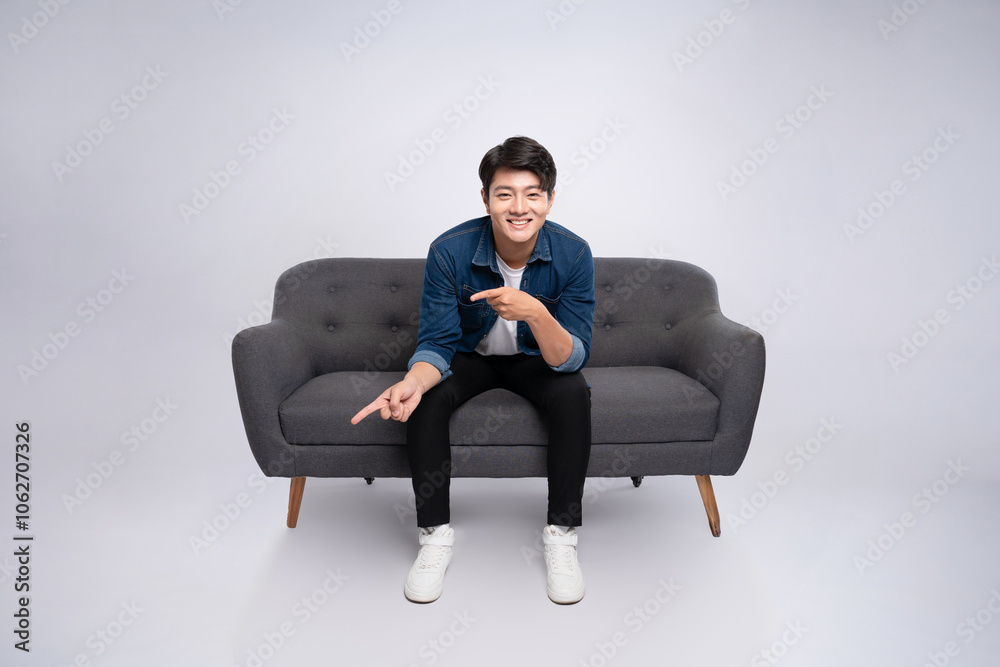 Full body image of young Asian man posing on sofa on white background Full body image of young Asian man posing on sofa on white background