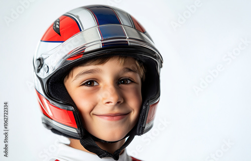 A young boy wearing a helmet with a red stripe on it. He is smiling and looking at the camera