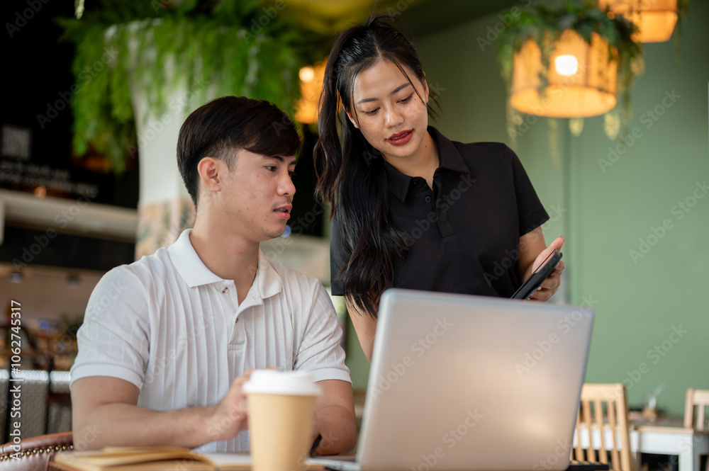 Two focused Asian colleagues are looking at a tablet screen, discussing its content, brainstorming. Two focused Asian colleagues are looking at a tablet screen, discussing its content, brainstorming.
