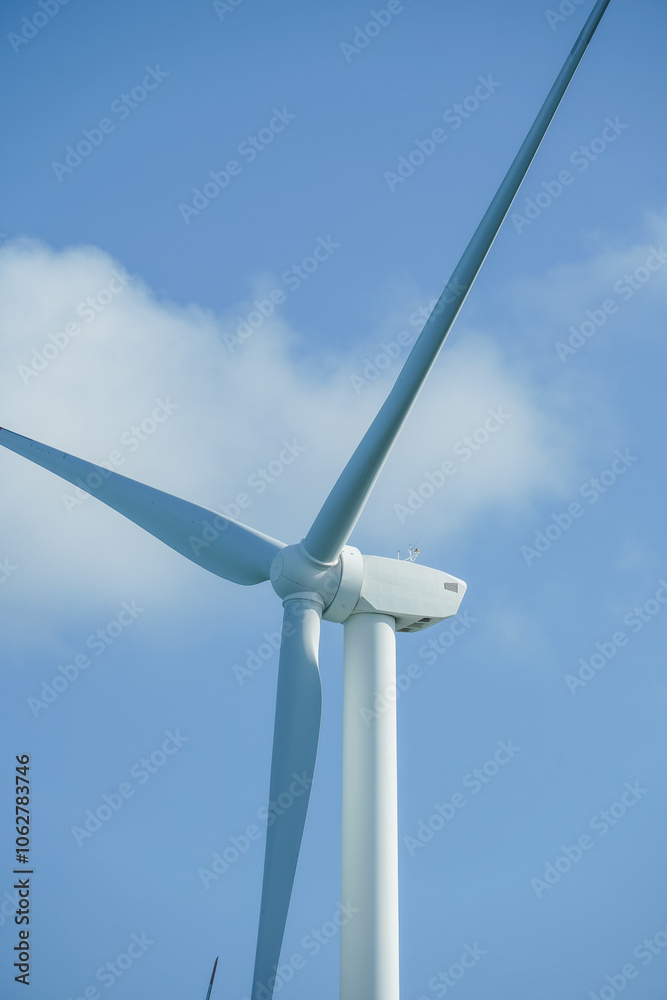A large wind turbine for generating electricity using the force of the wind installed in an agricultural field against a blue sky. A large wind turbine for generating electricity using the force of the wind installed in an agricultural field against a blue sky.