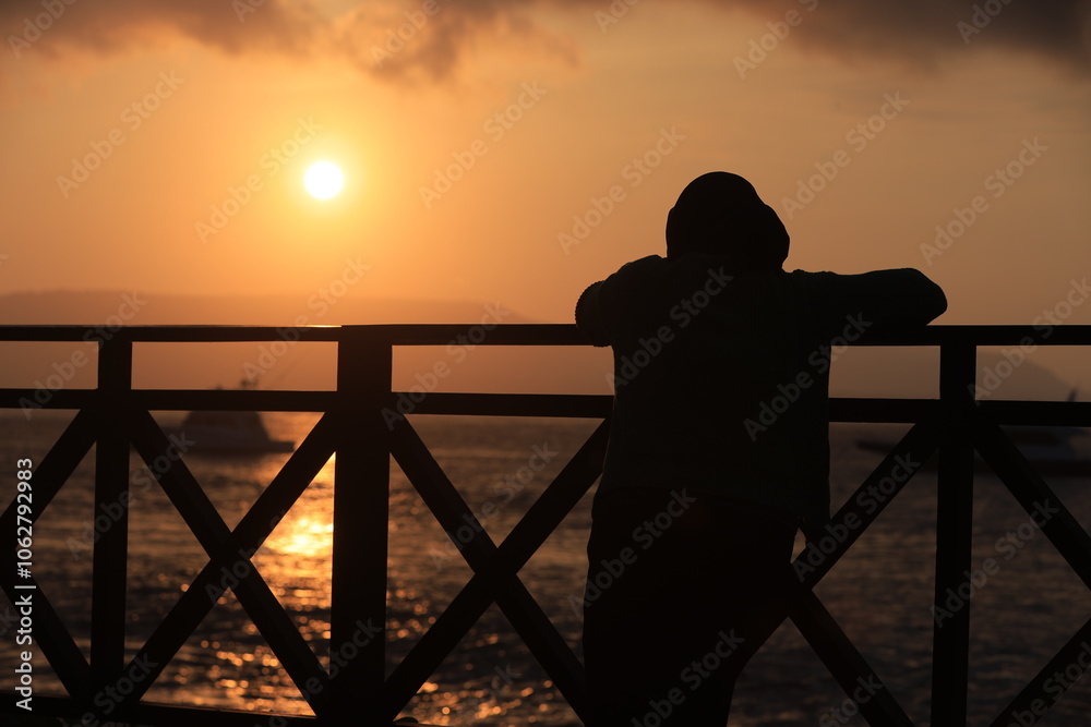 Obraz premium Silhouette figure at sunset on a calm beach with , bridge and ocean.