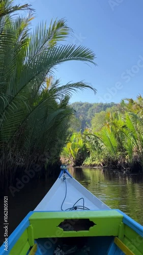 Boat ride along a river in ramang ramang sulawesi surrounded by mangroves and green limestone mountains on a sunny day in asia.
