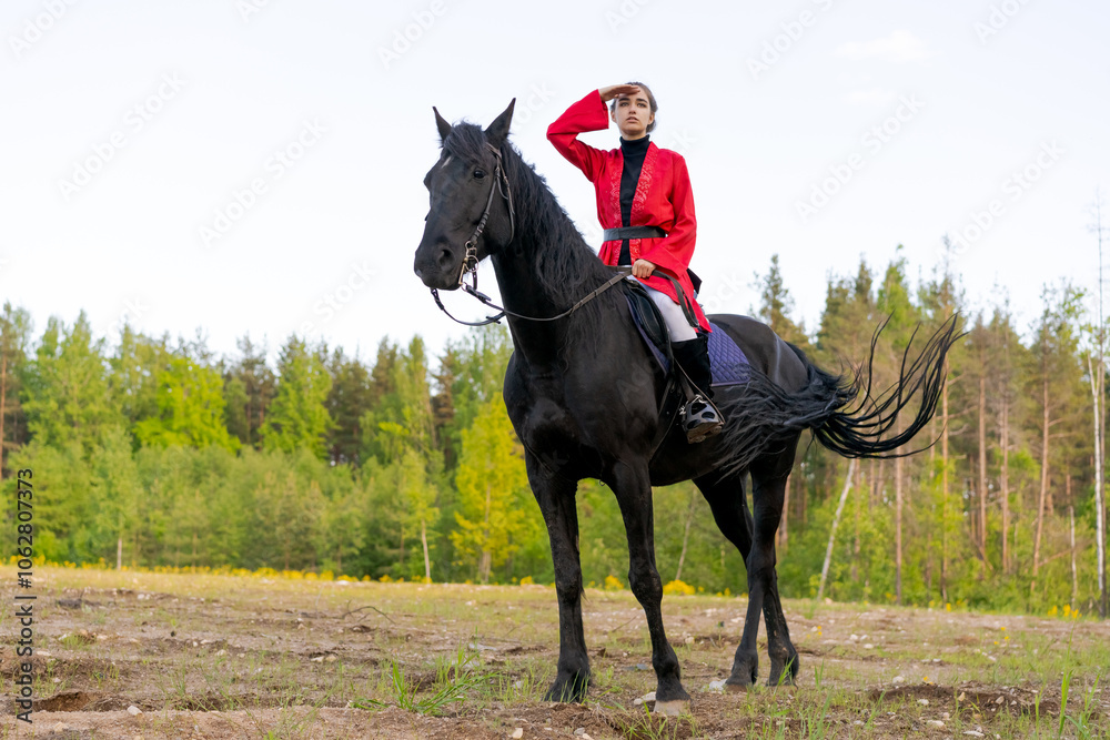Woman is riding a black horse in a field Woman is riding a black horse in a field