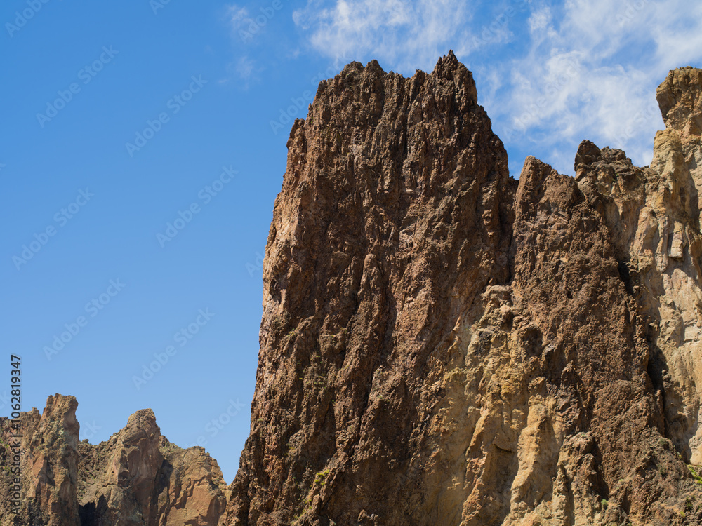 A rocky mountain with a clear blue sky in the background A rocky mountain with a clear blue sky in the background