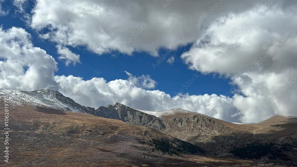 The rugged beauty of the Rocky Mountains, their peaks dusted with snow and rising dramatically against a vibrant blue sky dotted with fluffy white clouds. 4K. Time Lapse. The rugged beauty of the Rocky Mountains, their peaks dusted with snow and rising dramatically against a vibrant blue sky dotted with fluffy white clouds. 4K. Time Lapse.