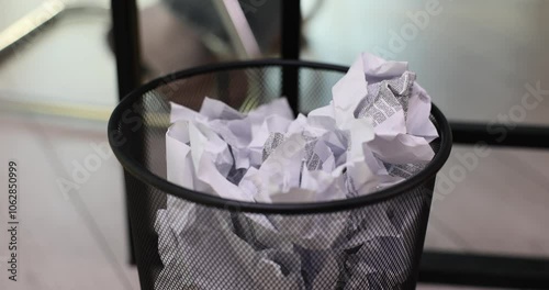 Crumpled paper is thrown into trash can in office photo