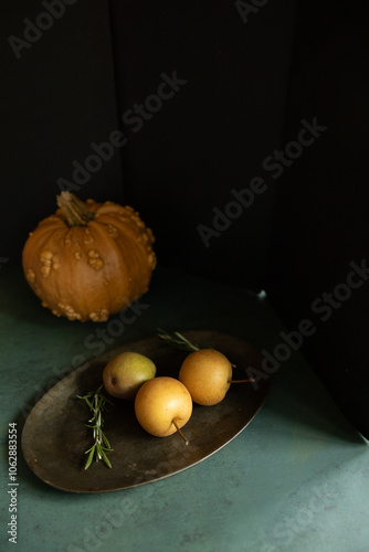 Rustic still life with pumpkin, pears, and rosemary on a dark tray photo