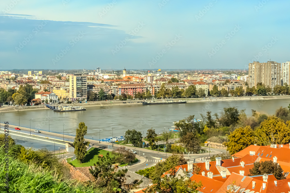 Naklejka premium cityscape of Novi Sad from the historic vantage point of Petrovaradin, where ancient towers and charming streets intertwine with the gentle flow of the Danube.