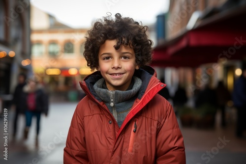 portrait of a little boy in red jacket at the city street photo