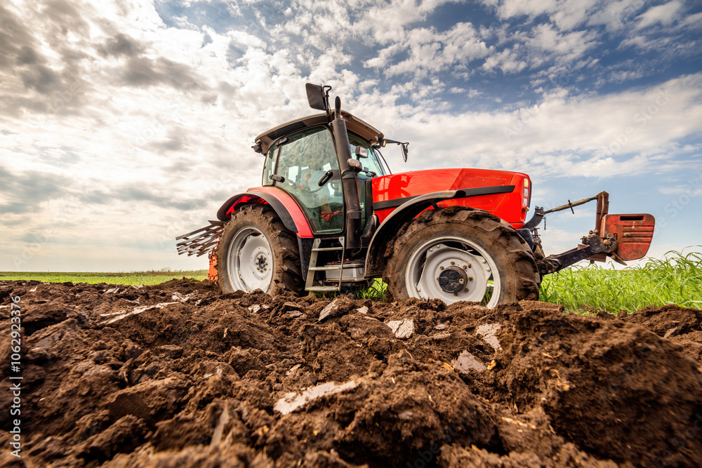 Powerful tractor turns the soil, readying the field for planting under a dramatic sky Powerful tractor turns the soil, readying the field for planting under a dramatic sky