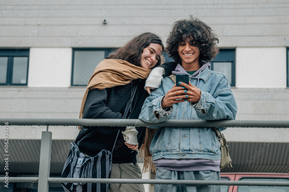 happy teenagers on the street looking at mobile phone happy teenagers on the street looking at mobile phone