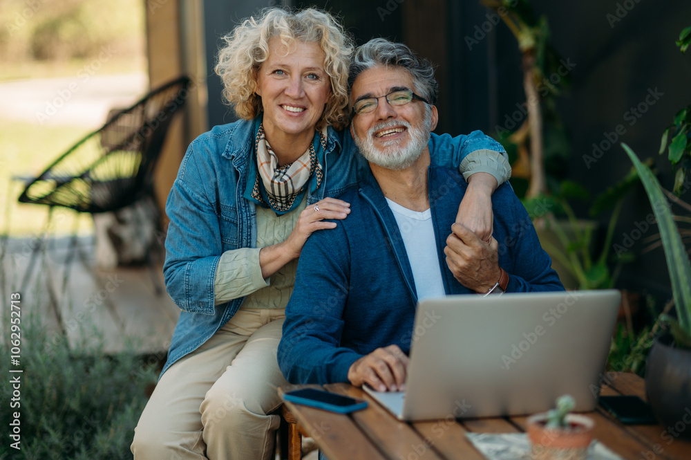 Middle-age couple smiling confident using laptop in the garden. Middle-age couple smiling confident using laptop in the garden.