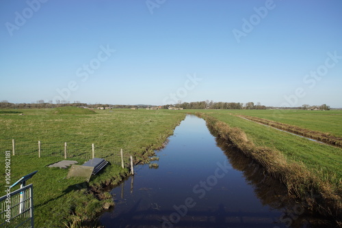 Dutch pasture landscape. Ditch, water, meadows. Concrete bunkers from the Second World War in the distance. Near village of Bergen. Autumn, Holland.	