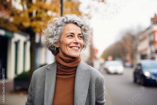 Portrait of a beautiful middle-aged woman in a gray coat and scarf on the street