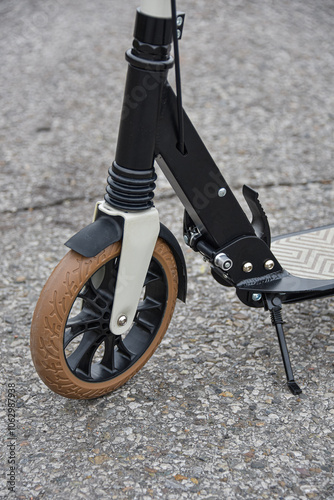 Front wheel of a scooter on asphalt. Close-up.