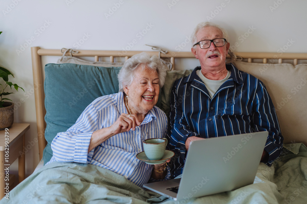 Happy senior man and woman using laptop on bed at home Happy senior man and woman using laptop on bed at home