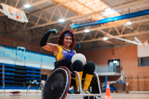 Happy mature disabled rugby player flexing muscle in wheelchair at sports court photo