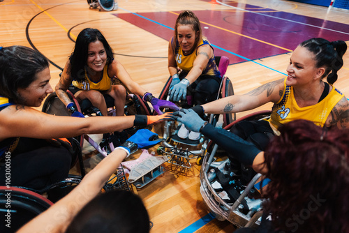 Happy disabled athletes stacking hands together before match at sports court photo