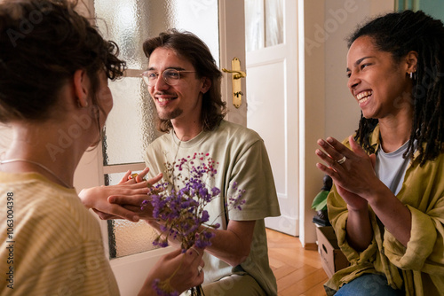 Happy friend clapping for man and woman getting engaged at home