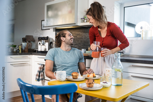 Happy man and woman having breakfast together at table in kitchen