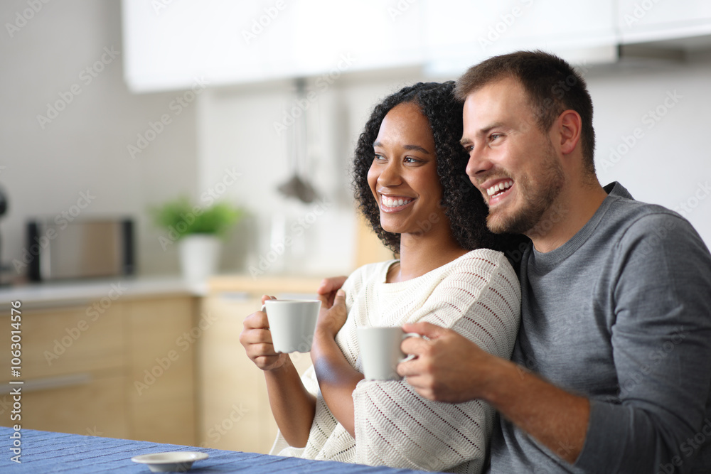 Happy interracial couple drinking in the kitchen Happy interracial couple drinking in the kitchen