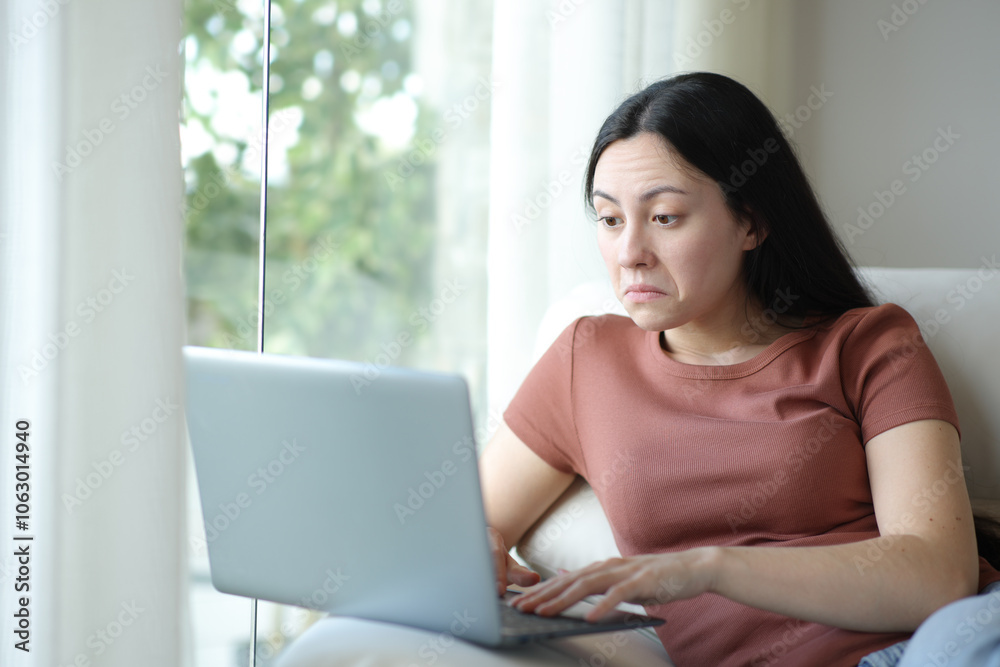 Perplexed asian woman using laptop at home Perplexed asian woman using laptop at home