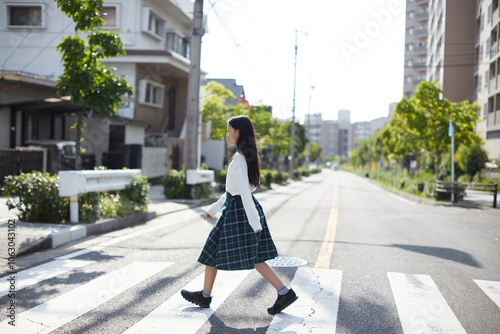 秋の昼の住宅街で横断歩道を渡る一人の小学生の女の子の姿 photo