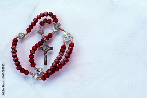 Red wooden Rosary with cross floating on white background. Symbol of Christian