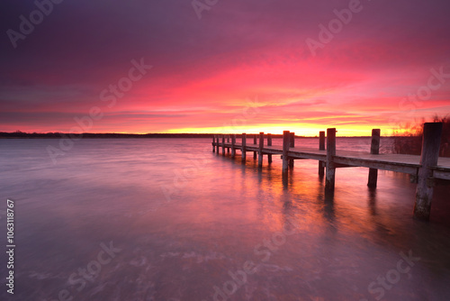 long wooden rustic pier at the lake with amazing purple sky