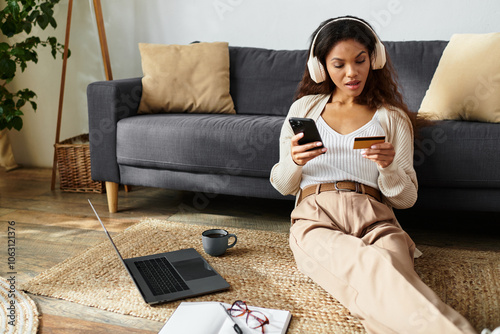 In a stylish living room, a woman comfortably shops online, enjoying music and a warm drink. photo