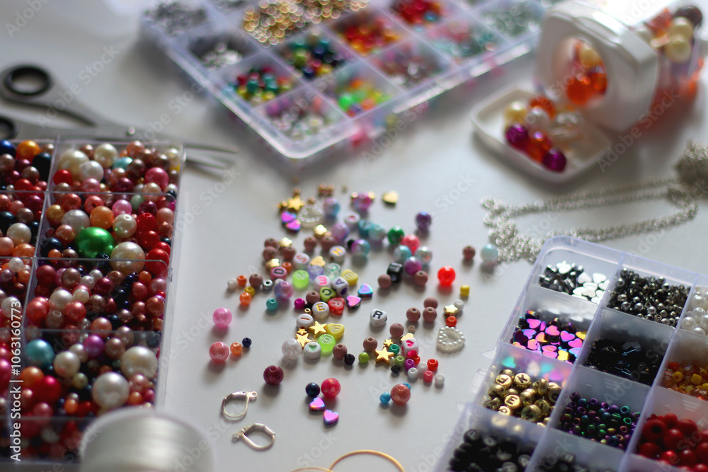 Colorful beads, letter beads, threads and other jewelry making supplies on white background. Making friendship bracelets concept. Selective focus.