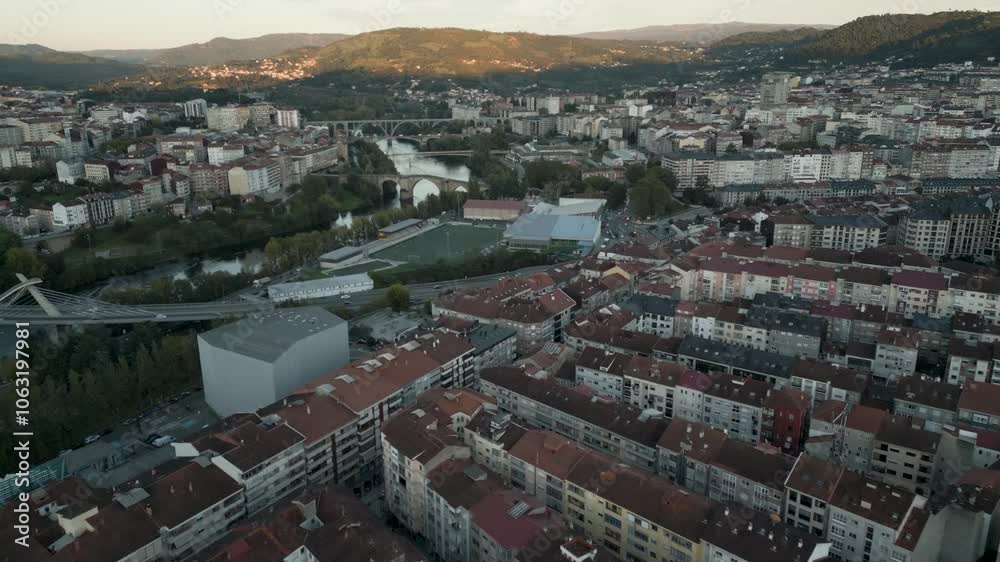 Aerial establishing overview above Ourense city with views of iconic bridges crossing water at sunset Aerial establishing overview above Ourense city with views of iconic bridges crossing water at sunset