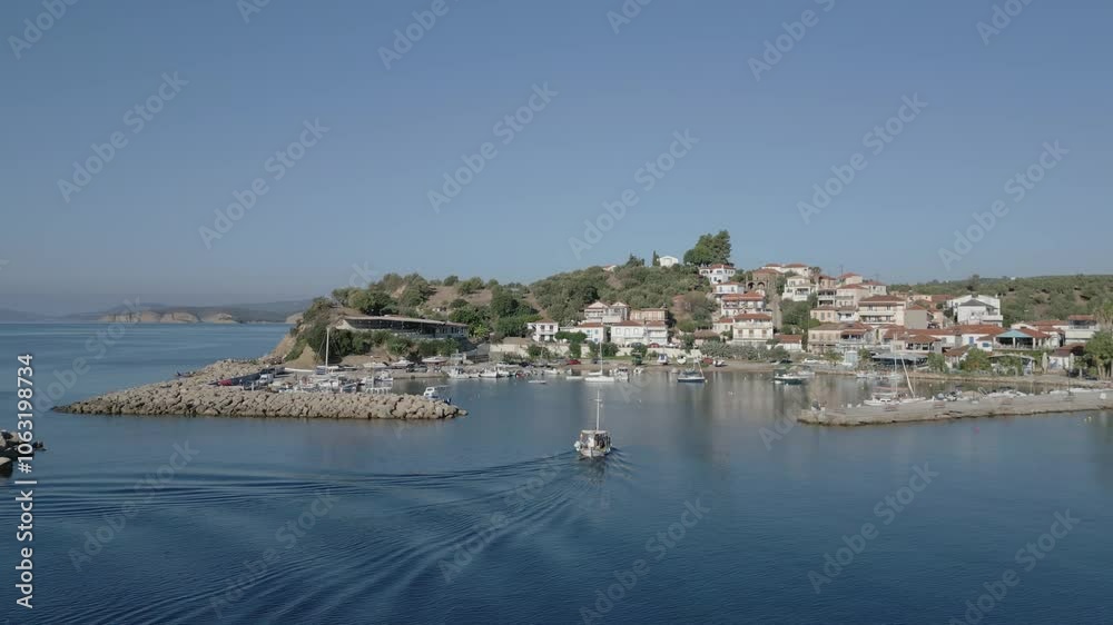 Capture a morning aerial view of the traditional village of Foinikounta, with a fishing boat departing from the port Capture a morning aerial view of the traditional village of Foinikounta, with a fishing boat departing from the port