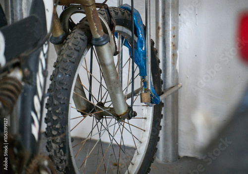 Rusty old bicycle front wheel locked and secured to metal bike stand.